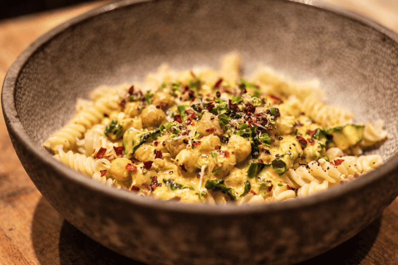 Kürbis-Pasta mit Zucchini, Käse und Gewürzen in einer Schüssel.