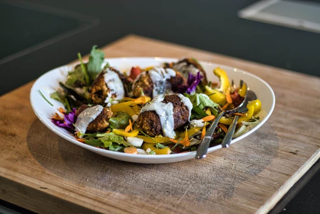 Vegane Köfte mit Salat und Joghurt-Dressing auf Teller.