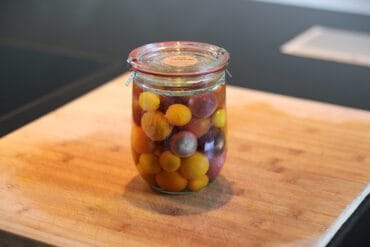 Fermentierte Weintrauben in einem Glas auf Holzbrett.