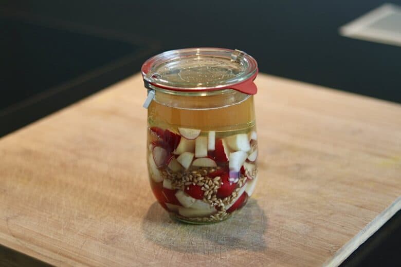 Fermentierter Bierrettich in einem Glas mit Knoblauch und Gewürzen.