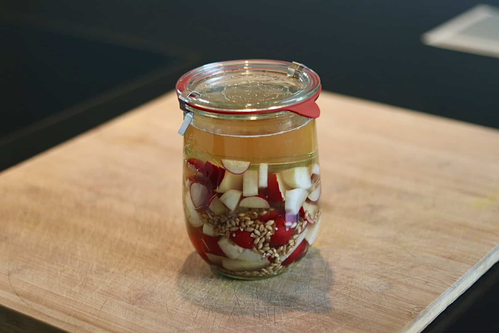 Fermentierter Bierrettich in einem Glas mit Knoblauch und Gewürzen.