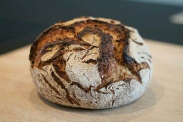 Handgefertigtes Sauerteigbrot mit knuspriger Kruste auf Holzbrett.