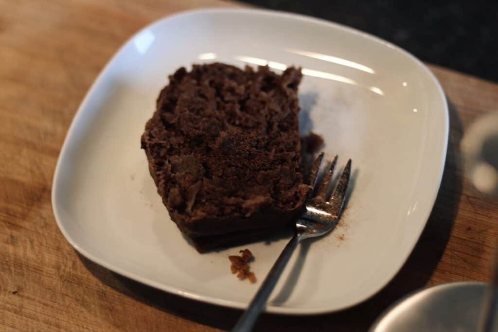 Schokoladen-Kuchen auf weißem Teller mit Gabel, lecker und saftig.