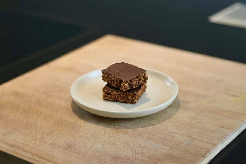 Veganer Müsliriegel mit Schokoladenglasur auf weißem Teller.