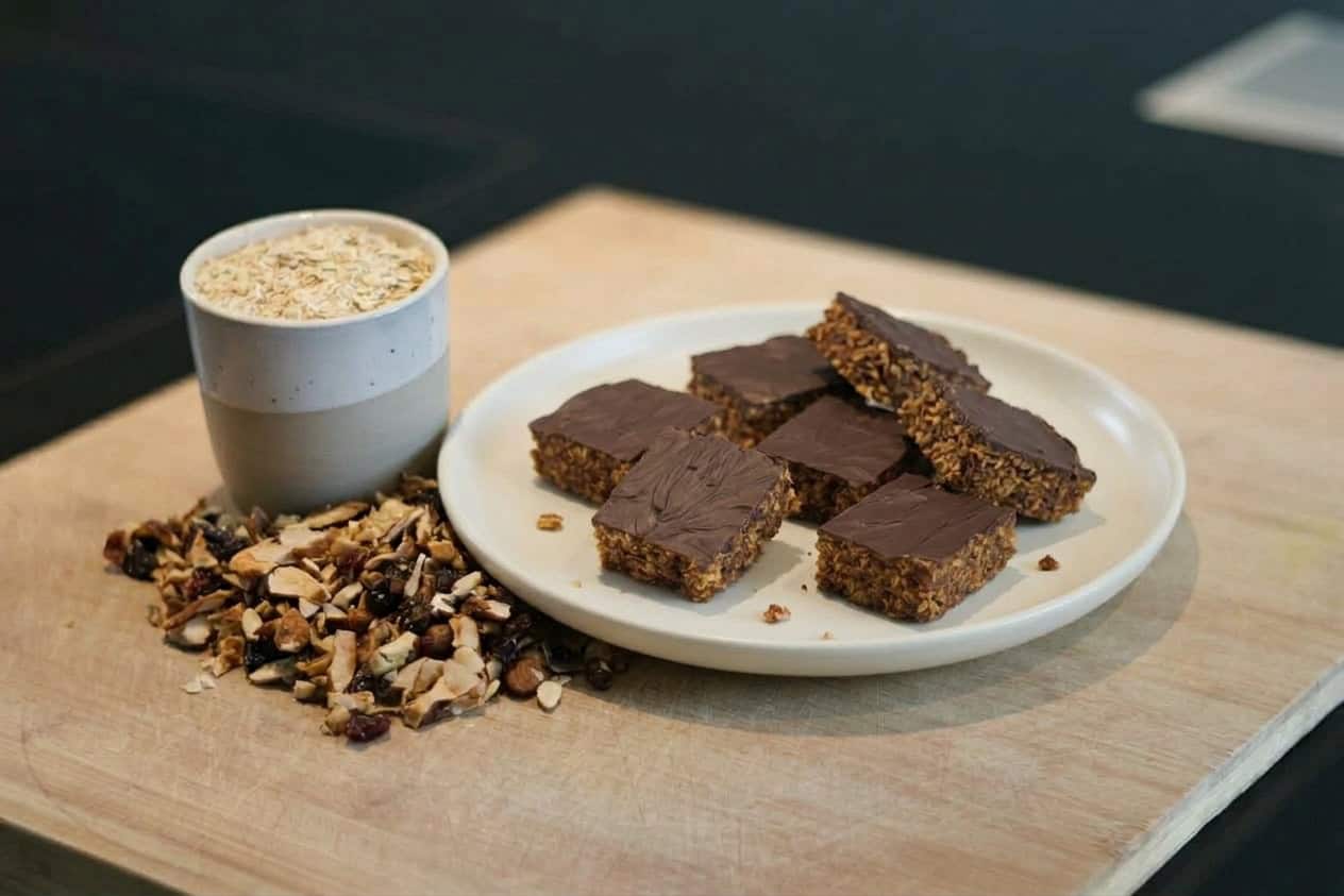 Gesunde Müsliriegel mit Kaffee auf Holzbrett.