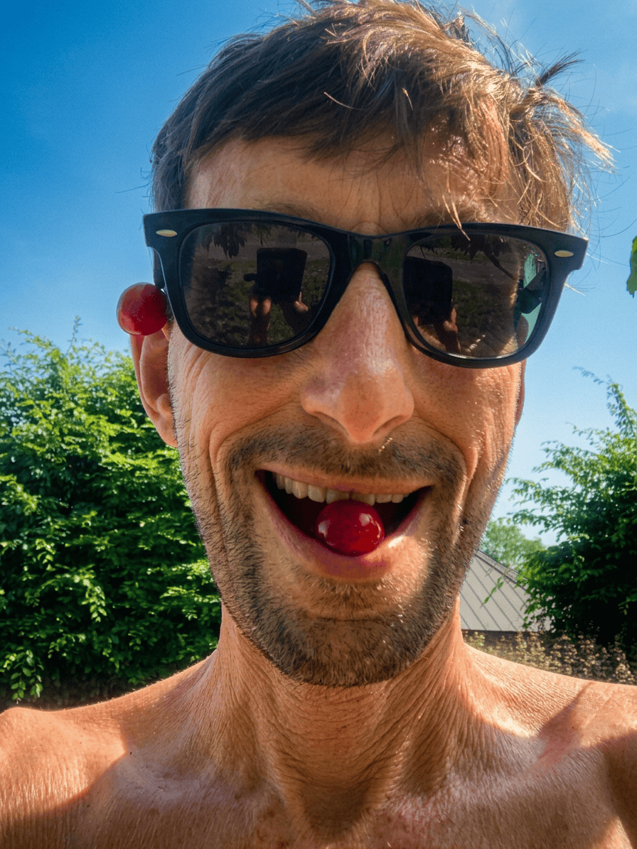 Sommerlicher Spaß im Garten Mann mit Sonnenbrille und freiem Oberkörper im Garten.
